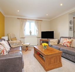 A living room with two sofas a wooden coffee table a lounge chair a television and window with curtains at Wheal Kendall in Mevagissey