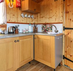 A kitchen corner with wooden cabinets a sink a kettle a toaster cups and utensils at Packhorse Shepherds Hut in Alderwasley near Wirksworth
