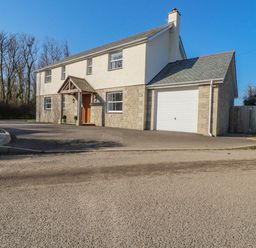 A two story house with a garage and driveway surrounded by trees at Ilgram in St Newlyn East