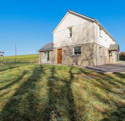 A two story house with a stone and white exterior next to a lawn and a driveway at Ilgram in St Newlyn East