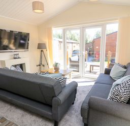 A living room with two gray sofas a wooden coffee table a floor lamp and a wall-mounted television at Eden Lodge - Sherwood 21 in South Lakeland Leisure Village