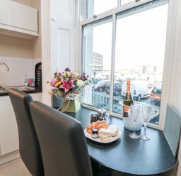 A kitchen with black countertop seating two black chairs and items including flowers food and drink on the table at Sunset View in Whitby