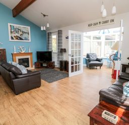 A living room with two leather sofas a fireplace and a television at Sea View Lodge in Eastfield Hall near Warkworth