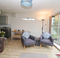 A living room with two armchairs and a sliding glass door opening to a balcony at 17 Coedrath Park in Saundersfoot