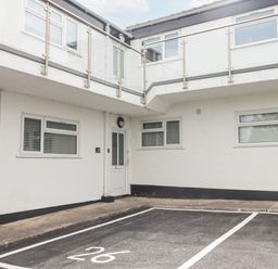A white exterior building with multiple windows a white door and parking spaces marked on the ground at 26 Coedrath Park in Saundersfoot