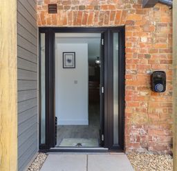 A front door entrance with a welcome mat and brick wall at Bumblebee Cottage in East Nynehead near Bradford-On-Tone