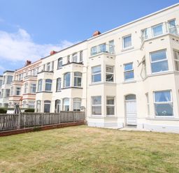 Exterior view of a row of multi-story residential buildings with bay windows and fenced yards at Gwel Y Mor in Pwllheli