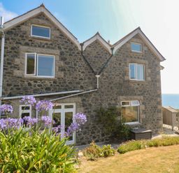 A house with stone exterior and windows overlooking the sea at Penmarth House Coverack