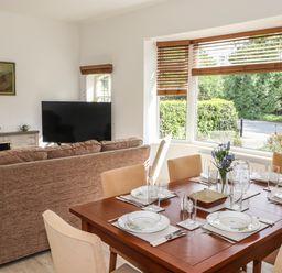 A dining table set with plates glasses and cutlery next to a sofa and a television in a living room at Halewood in Bowness-On-Windermere
