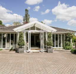 Front of a single story house with large glass doors and windows with plants in pots at The River House Avon Valley Stonehenge with fishing Salisbury