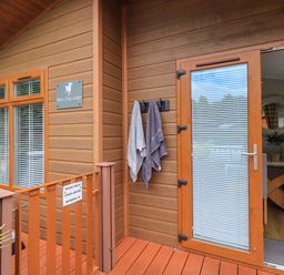 Exterior wooden deck with towels hanging near a glass door leading to a dining area at Black Dog Lodge Thirlmere 3 White Cross Bay near Windermere