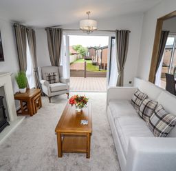 A living room with a sofa armchair coffee table fireplace and sliding glass doors at Bramblewick in Runswick Bay near Staithes
