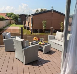 An outdoor patio with wicker chairs and a table with drinks and flowers at Bramblewick in Runswick Bay near Staithes