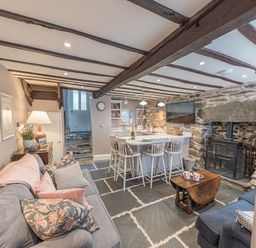 A living area with sofas pillows a small wooden table kitchen island stools and a stove at Old Toffee Shop in Ambleside