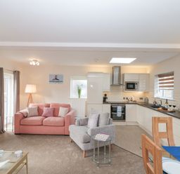An open plan living room and kitchen with sofas a dining table and kitchen appliances at Weydale Avenue in Scarborough