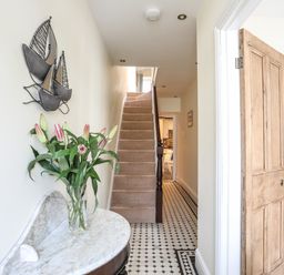 A hallway with a staircase a wooden door and a marble table with flowers at Hyfrydle in Borth-Y-Gest