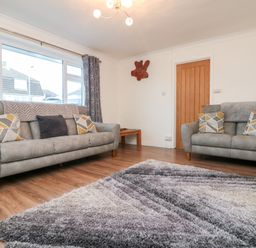 A living room with two gray sofas a wooden door and a patterned rug on a wooden floor at Summerhayes Park Bottom