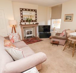 A living room with a sofa and armchair near a fireplace and television at Beals Yard in Alnwick