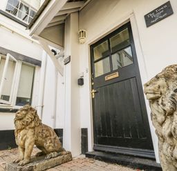 The black front door with two stone lion statues outside at The Town House in Dorchester