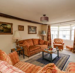 A living room with patterned sofas armchairs coffee table and paintings on the wall at The Town House in Dorchester