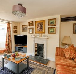 A living room with sofas a coffee table fruit snacks and a television at The Town House in Dorchester