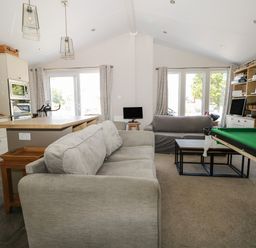 A living room with sofas a pool table a coffee table and kitchen island at The Goodwood Lodge in Runcton near Chichester
