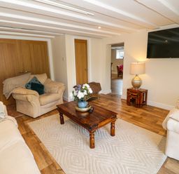 A living room with sofas a wooden coffee table and a wall mounted tv at Plas Eithin in Mynydd Mechell near Llanfechell