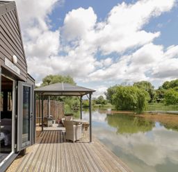 An outdoor area with a deck and chairs at Oak Lodge At Bridge Lake Farm & Fishery in Chacombe