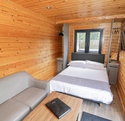 A bedroom with a bed and sofa at Oak Lodge At Bridge Lake Farm & Fishery Chacombe