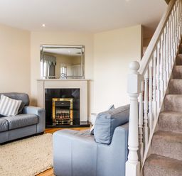 A living room with two blue sofas near a fireplace and a carpet adjacent to a staircase at Beach View in Duncannon near Ramsgrange County Wexford