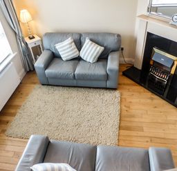 A living room with two sofas striped cushions a lamp a fireplace and a rug at Beach View Duncannon near Ramsgrange County Wexford