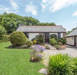 A small house with a slate roof surrounded by grass bushes and flowers at Wagtail Bradworthy near Bude