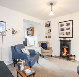 A living room with blue and beige armchairs a fireplace and framed pictures at Silva in Penmon