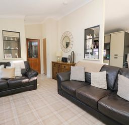 A living room with two dark sofas with cushions a wooden sideboard mirror and wall decoration at RoseGrace Lodge in Auchterarder