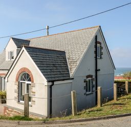 A house with a tiled roof near the coast with a view of the sea at Seagull Cottage in Bude