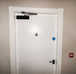 A white door with the number 4 and a black door closer at The Poppy Fields Abode in Dyserth