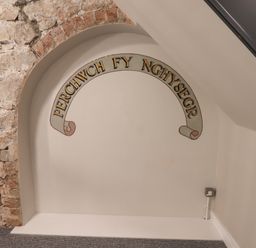 A stone archway with Welsh text painted on the wall at The Poppy Fields Abode in Dyserth