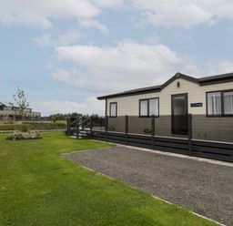 A static caravan with a small ramp and steps on a grassy plot at 14 Fairways in Burnham-On-Sea