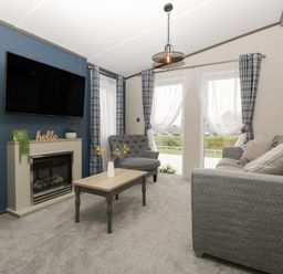A living room with a sofa armchair coffee table fireplace and television at 14 Fairways in Burnham-On-Sea