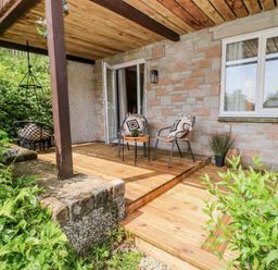 A wooden deck with chairs and a table at Lavender Lodge in St. Ann's Chapel, Cornwall