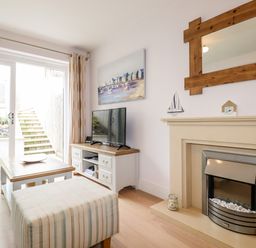 A living room with a fireplace tv and coffee table near sliding glass doors at 16 Ocean Heights in Newquay