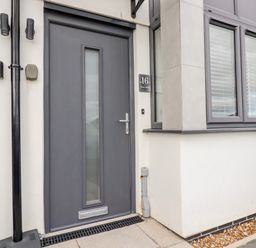 A grey front door with mail slot and handle next to a window with blinds at 16 Ocean Heights Newquay