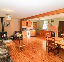 A living room with a wood stove sofa armchair wooden coffee table and dining table with chairs at Teach Chiuin Coolaheen near Cappoquin County Waterford