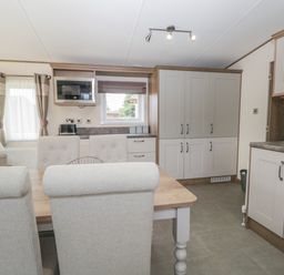 A kitchen and dining area with a wooden table and upholstered chairs at 22 Sherwood South Lakeland Leisure Village near Warton