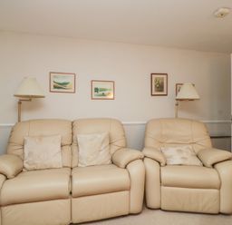 A living room with two leather sofas and paintings on the wall at Derwent Haven in Keswick
