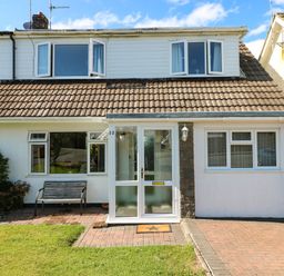 A front view of a semi detached house with a tiled roof a porch a driveway and a bench at 53 St Brides View Roch
