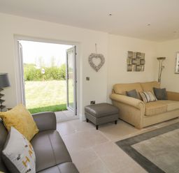 A living room with two sofas cushions and an open door to a garden at Garden Cottage in Upton Upon Severn