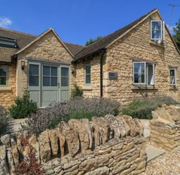 The exterior of a house with a stone wall and garden at 12 Manor Farm Close Kingham
