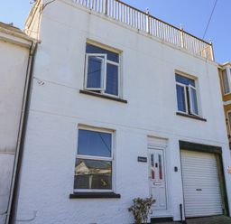 A white two-story house with windows a door and a garage door at Penmar in Looe