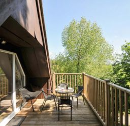 A balcony with a small round table and four chairs overlooking trees at 60 Valley Lodge in Callington near Gunnislake